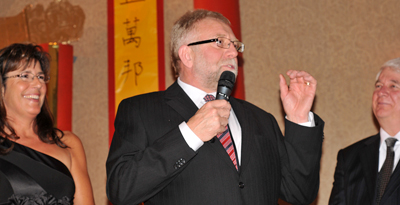 Caption info: Mark Brown, president of Northern Trailer and the Kamloops company's   former owner, offers a friendly challenge to the other business   leaders gathered at the 2010 TRU Foundation Gala to consider boosting   their financial support for the university. Brown had moments before   pledged $2 million to TRU, the largest-ever non-government gift to TRU.  On stage with him is his wife Ellen and TRU Board chair Karl deBruijn.  The event was held on the TRU Campus Activity Centre rotunda and in   the adjoining Grand Hall. The theme for the night was China's   Forbidden City.