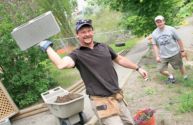 Larry Illes of TRU Career Education does his best strongman impression during TRU Career Education's turn at a United Way Day of Caring event. That's Cliff Robinson of TRU Counselling Services in the background and suitably impressed by Illes's strength.