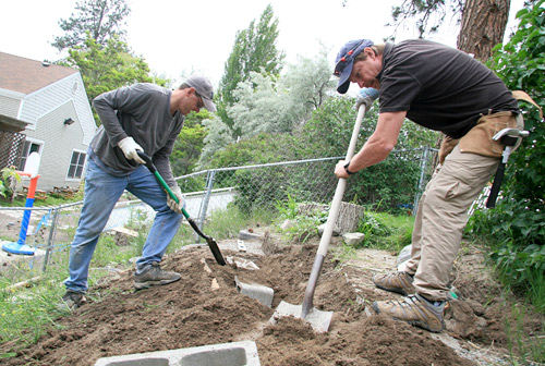 Sean Read and Larry Illes of TRU Career Education shovel & rake their way to buring concrete blocks for a terraced retaining wall.