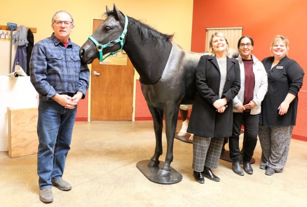 A group of people standing in front of a full-size horse replica