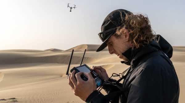 Man looks into a camera with a drone flying in the background.