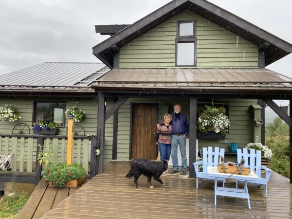 An older couple standing in front of a house.