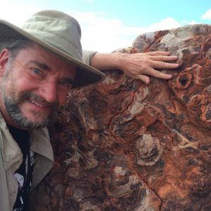 Dr. Bruce Damer stands next to a 3.6-billion-year-old artifact representing buried layers of molecular structures, thought to be the framework for the origin of life.