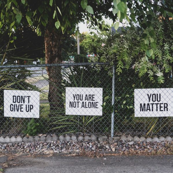 signs on a chainlink fence that say Don't Give up, You are not alone and You Matter