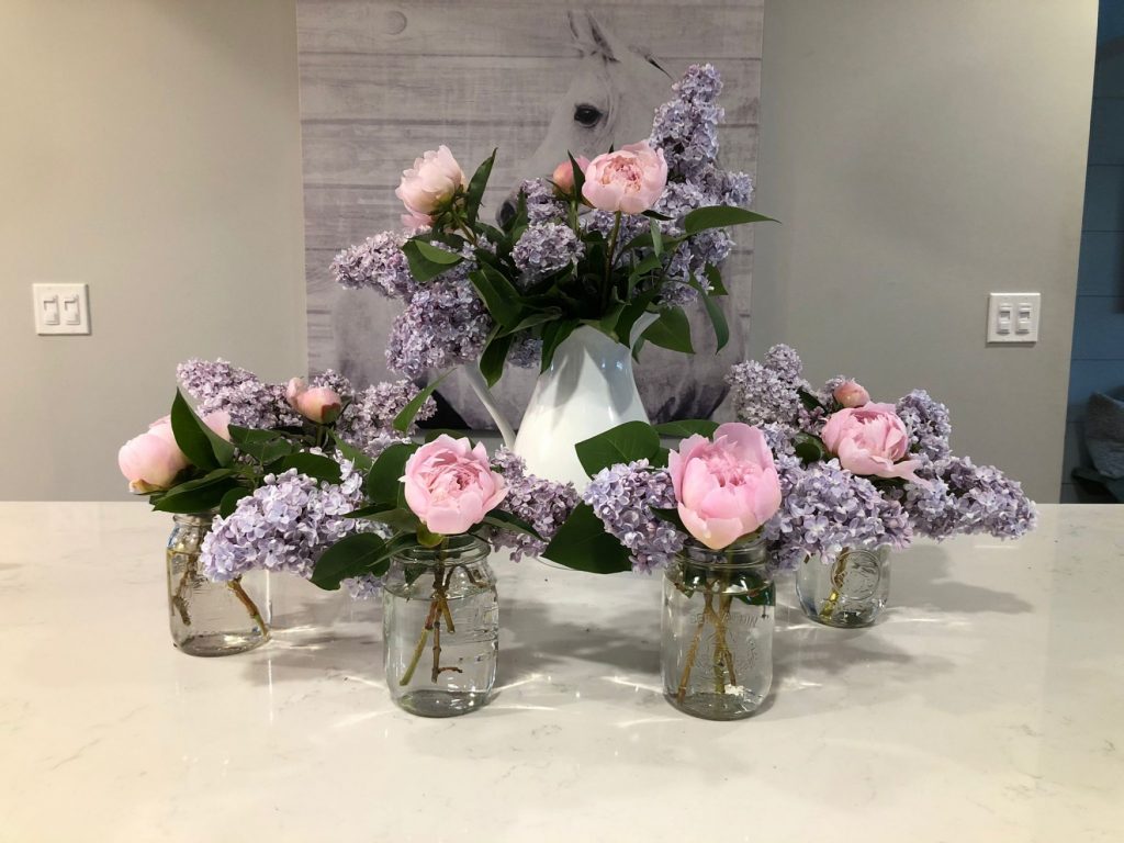 Jars of pink flowers on a table top.