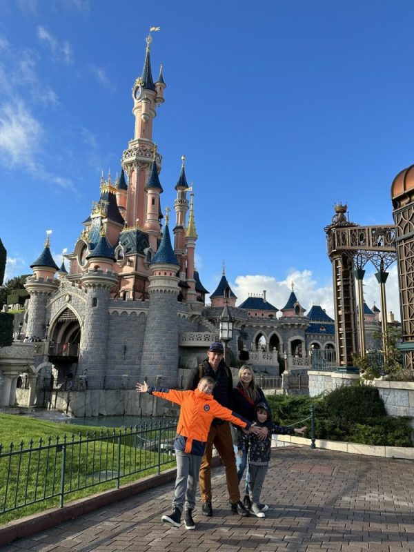 A family poses in front of Disneyland Paris.