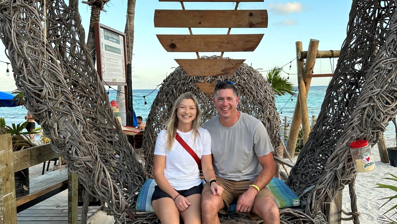 A couple sits on a bench at a beach resort.