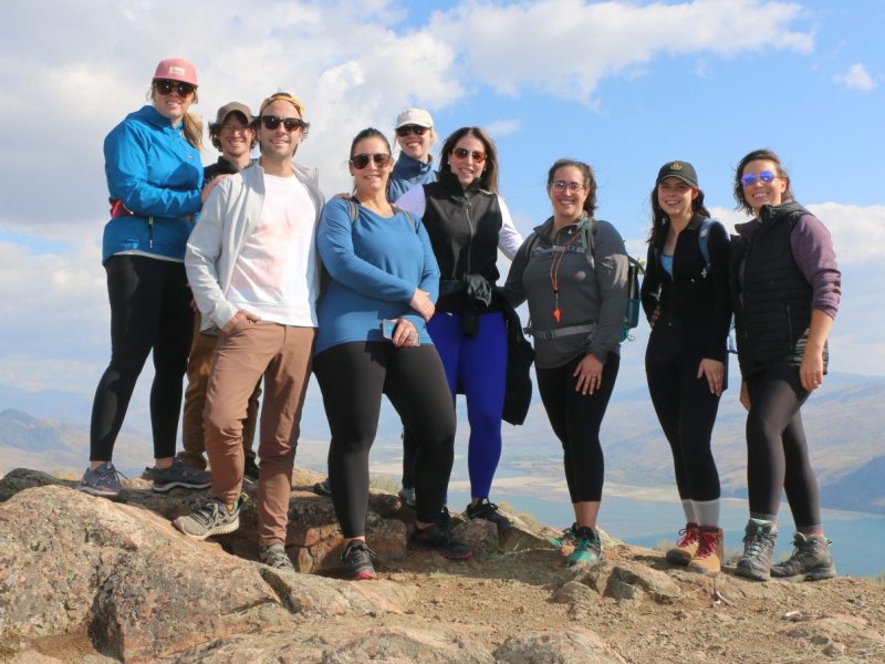 A group of people stand on the summit of a mountain.