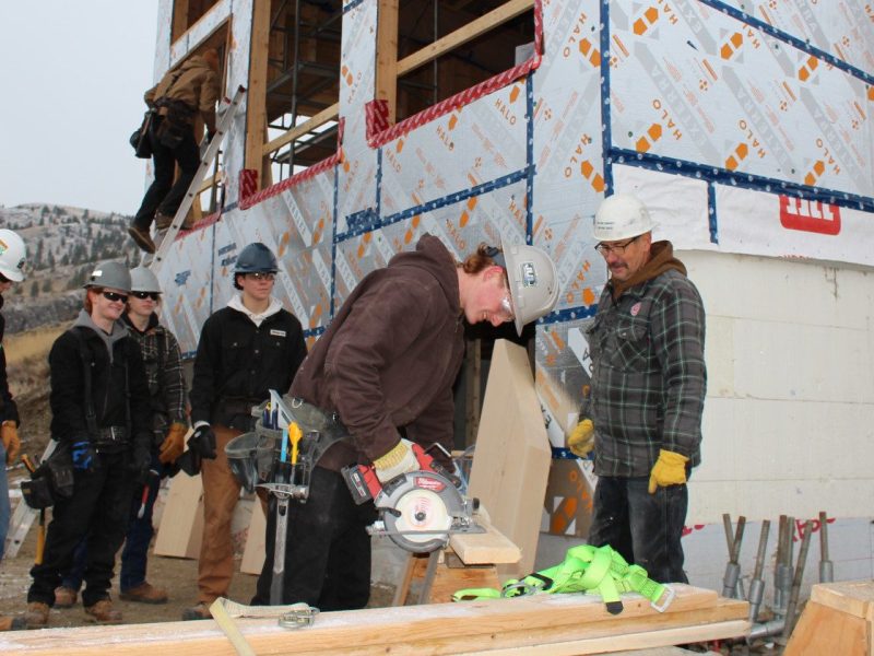 Carpentry instructor Tim Kasten (far right) on the site of the TRU Training House with a group of his students.